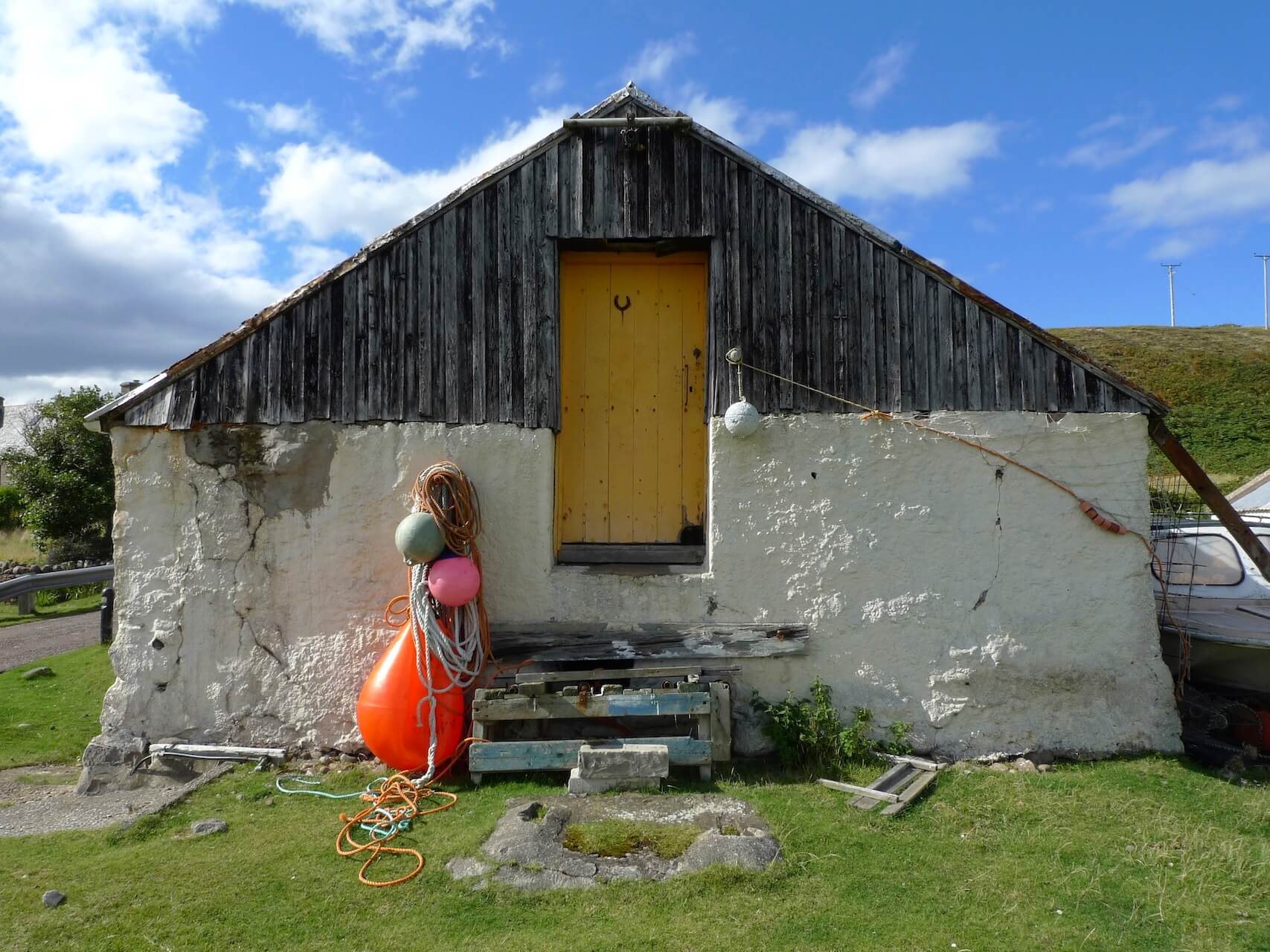 A sea shed with plastic buoys and fishing gear piled near the front door.