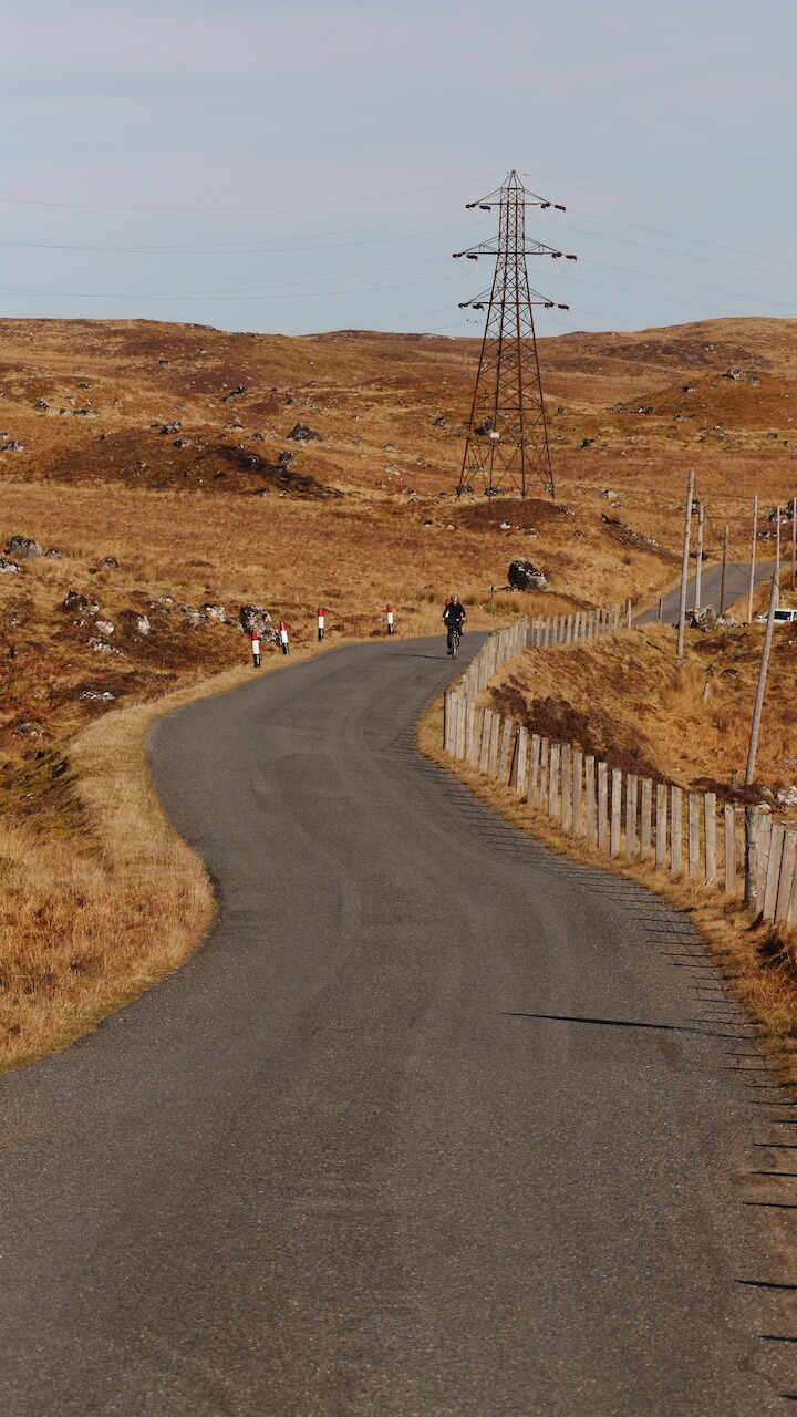 A cyclist descends on a single track road from Rannoch Station